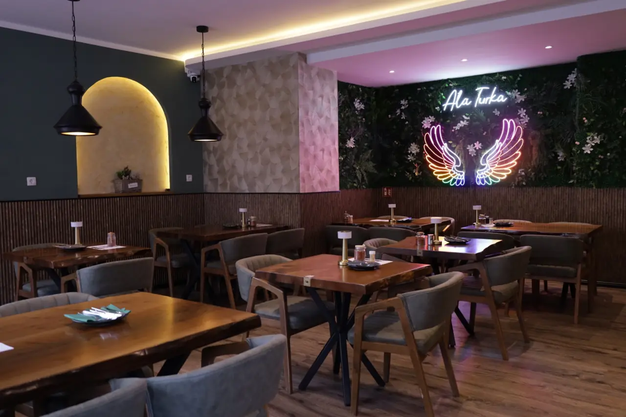 Gastraum des Ala Turka mit Holztischen und Neon-Schriftzug